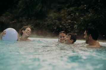Eine Familie genießt gemeinsam Zeit im Außenpool des Hotel Sonngastein im Salzburger Land.