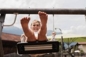 Ein lachendes Kind schaukelt mit Schwung auf dem Spielplatz beim Familienhotel Tirolerhof