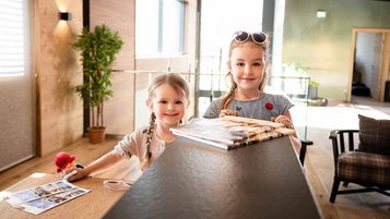 Zwei Mädchen an der Rezeption eines Familienhotels 