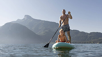 Oberösterreich im Sommer erleben: Vater und Kind fahren gemeinsam Stand Up Puddle auf dem Mondsee.