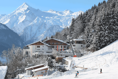 Blick auf das Familienhotel Amiamo im Winter, im Hintergrund ein schneebedeckter Berg 