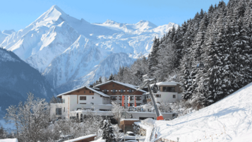 Blick auf das Familienhotel Amiamo im Winter, im Hintergrund ein schneebedeckter Berg 