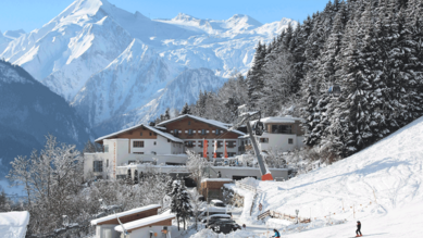 Blick auf das Familienhotel Amiamo im Winter, im Hintergrund ein schneebedeckter Berg 