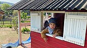 Junge schaut aus dem Fenster des Ziegenhauses auf dem Außengelände des Familienhotels Der Böhmerwald.