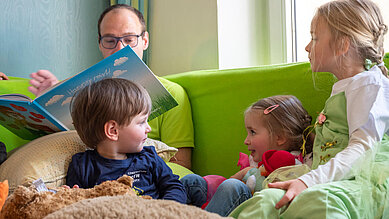 Betreuer liest Kinder ein Buch vor im Happy-Club im Familienhotel Mein Krug im Fichtelgebirge.