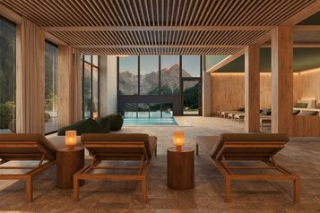 Hallenbad im Familienhotel Bella Vista in Südtirol mit Ruheliegen, Holzelementen und großen Fenstern zum Bergpanorama.