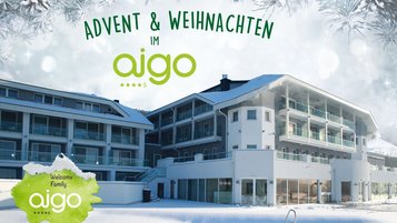 Das moderne Familienhotel aigo im Böhmerwald liegt in verschneiter Landschaft, darüber steht die Schrift „Advent & Weihnachten im aigo“