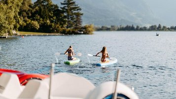 Kinder beim Stand-up-Paddling auf dem See im Sommer nahe dem Familienhotel Amiamo im Salzburger Land.