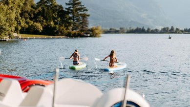 Kinder beim Stand-up-Paddling auf dem See im Sommer nahe dem Familienhotel Amiamo im Salzburger Land.