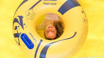 Ein Kind schaut durch einen Rutschreifen, mit dem man eine Wasserrutsche im Familienhotel rutschen kann.