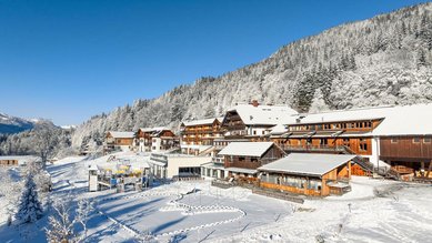 Winteransicht des verschneiten Familienhotels Ramsi in den Bergen mit direktem Zugang zur Natur.