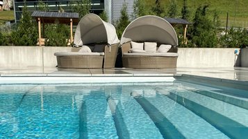 Blick auf den Infinity-Pool mit Liegeinseln im Familienhotel Bella Vista in Südtirol