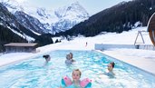 Kinder schwimmen im Außen-Pool im Winter.