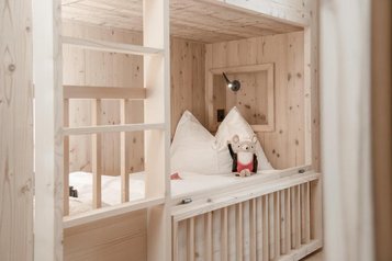 Ein Holzbett als Stockbett im Zimmer des Familienhotels Gorfion in Liechtenstein.