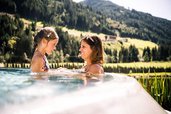 Mutter und Tochter lachen gemeinsam im beheizten Outdoor-Pool des Familienhotel Alpura Retreat in Südtirol.