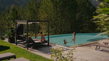 Familie genießt die Sonne und planscht im Außenpool des Familienhotels Engel Gourmet & Spa