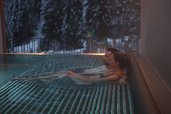 Paar genießt entspannte Momente im warmen Outdoor-Pool mit Winterblick im Familienhotel Habachklause.