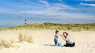 Mutter und Sohn spielen im Sand am deutschen Ostseestrand.