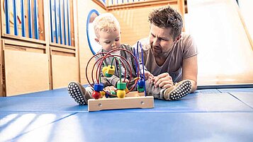 Ein Vater spielt mit seinem Baby in einem Familienhotel 