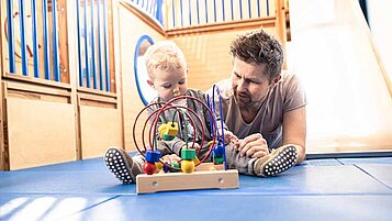 Ein Vater spielt mit seinem Baby in einem Familienhotel 