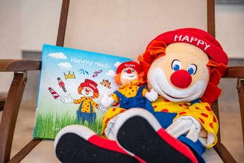 Maskottchen Happy als Kuscheltier mit Buch im Familienhotel Bruckwirt, das Kinder im Urlaub begleitet.