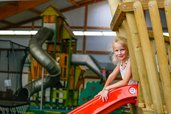 Mädchen auf der Rutsche im großen Indoorspielplatz des Familienhotels Sonnenhügel in der Rhön.