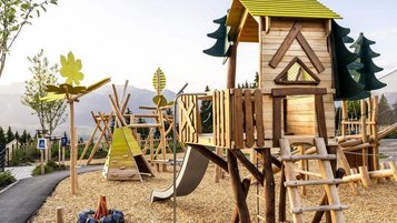 Auf dem Kastanienspielplatz des Familienhotels Allgäuer Berghof im Allgäu steht ein großer Holzspielplatz mit Spielturm, Rutsche und Kletterelementen.