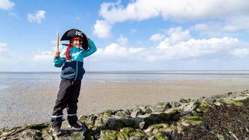 Kleiner Junge spielt im Piratenkostüm an der Nordsee.