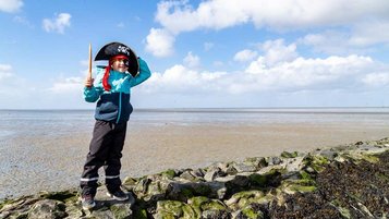 Kleiner Junge spielt im Piratenkostüm an der Nordsee.