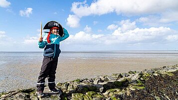 Kleiner Junge spielt im Piratenkostüm an der Nordsee.
