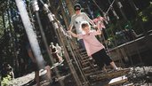 Ein Mädchen balanciert im Outdoor-Kletterpark zwischen Seilen und Holzelementen im Familienurlaub im Wellness- & Familienhotel Egger.