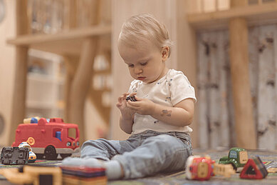 Kleinkind sitzt im Happy-Club des Familienhotels Gorfion und spielt mit Spielsachen