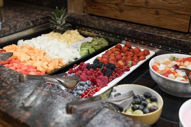 Frisches Obstbuffet im Familienhotel Oberkarteis mit einer bunten Auswahl an Beeren, Melonen, Kiwi und Ananas.