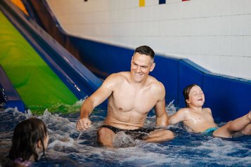 Vater und Kinder haben Spaß beim Rutschen im Hallenbad des Familien Resort Petschnighof in Kärnten.