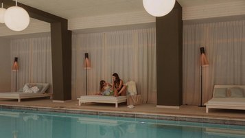 Mutter und Tochter lesen auf der Ruheliege im Hallenbad des Familienhotels Engel Gourmet & Spa gemeinsam ein Kinderbuch.