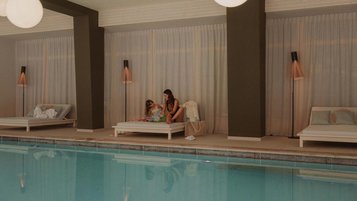Mutter und Tochter lesen auf der Ruheliege im Hallenbad des Familienhotels Engel Gourmet & Spa gemeinsam ein Kinderbuch.