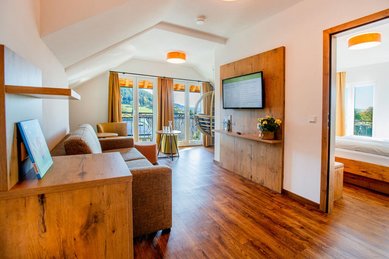 Großzügiger Wohnbereich mit Sofa, Holzmöbeln, Fernseher und Balkonzugang in einer Suite des Hotel Engel im Schwarzwald