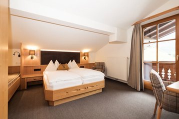 Gemütliches Familienzimmer im Familienhotel Oberkarteis mit Doppelbett, Balkon und hellen Holzmöbeln für eine erholsame Auszeit.