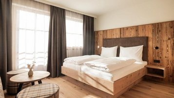 Gemütliches Familienzimmer im Familienhotel Oberkarteis mit Doppelbett, Balkon und hellen Holzmöbeln für eine erholsame Auszeit.