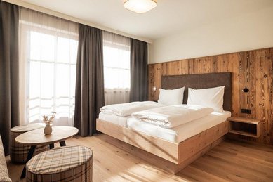 Gemütliches Familienzimmer im Familienhotel Oberkarteis mit Doppelbett, Balkon und hellen Holzmöbeln für eine erholsame Auszeit.