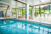 Schwimmbad mit einer Brücke und Panoramaausblick auf die Landschaft des Familienhotels Sonngastein in Bad Gastein.