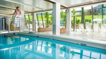 Schwimmbad mit einer Brücke und Panoramaausblick auf die Landschaft des Familienhotels Sonngastein in Bad Gastein.