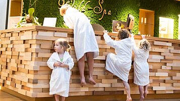 Kinder stehen an der Rezeption im hoteleigenen Wellnessbereich des Familienhotels Ulrichshof im Bayerischen Wald. Der Wellnessbereich bietet auch für Kinder einige Angebote an.