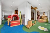 Großzügiger Indoor-Spielraum mit buntem Boden, Holzspielgeräten und Kletterelementen für Kinder im Hotel Engel im Schwarzwald