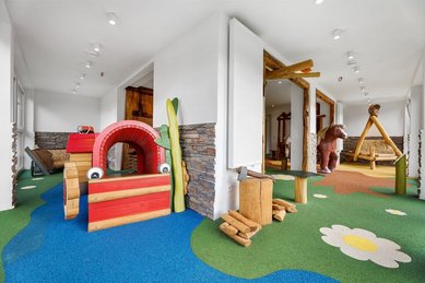 Großzügiger Indoor-Spielraum mit buntem Boden, Holzspielgeräten und Kletterelementen für Kinder im Hotel Engel im Schwarzwald