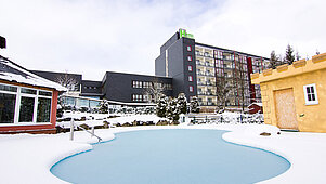 Die Hotelanlage vom Familotel Am Rennsteig im Winter mit zugefrorenem Außenpool