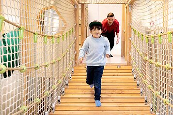 Junge läuft über die Hängebrücke im Happy-Club des Familienhotels Sonnenpark.