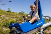 Ein Kind fährt direkt hinter dem Hotel Alpengasthof Hochegger in Kärnten mit der Sommerrodelbahn.
