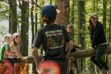 Kinder und eine Betreuerin erkunden gemeinsam den Wald beim Naturprogramm im Familienhotel Tiolerhof