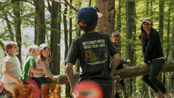 Kinder und eine Betreuerin erkunden gemeinsam den Wald beim Naturprogramm im Familienhotel Tiolerhof